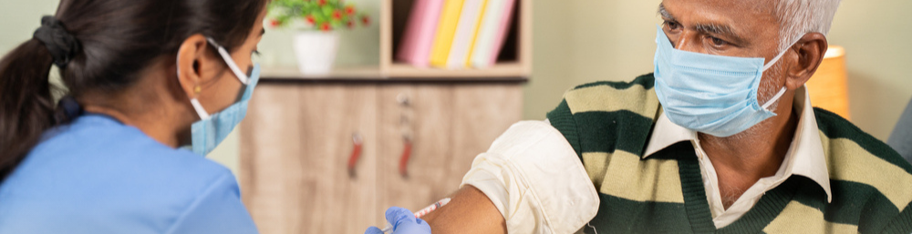 A Caretaker giving injection an elderly with cancer